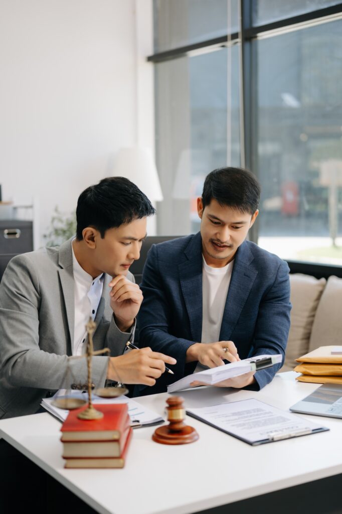 Asian business team and lawyers discussing contract papers sitting at the table.