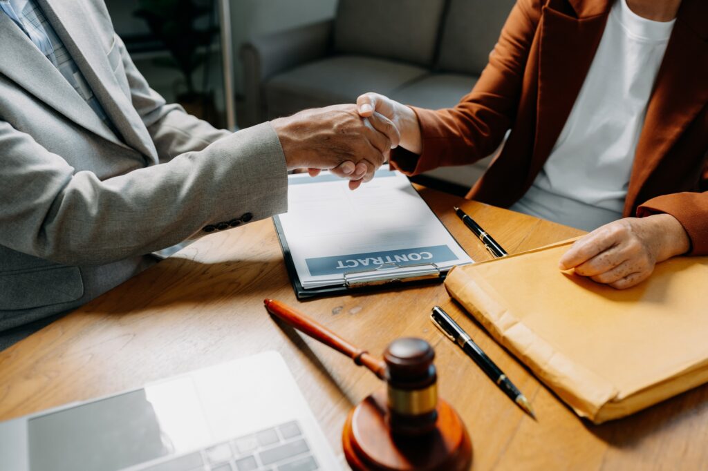 Middle age partner lawyers attorneys shaking hands after discussing a contract agreement done.